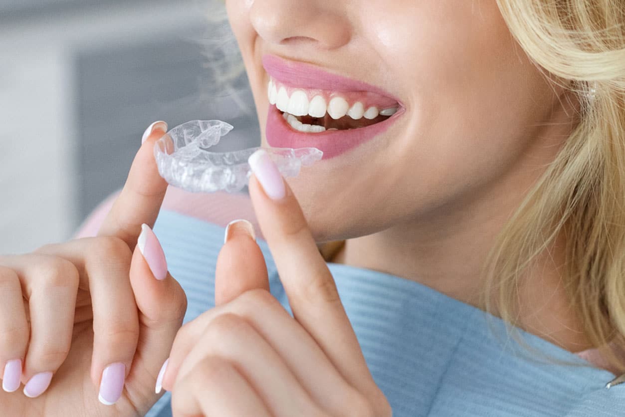 Woman putting Invisalign on her teeth