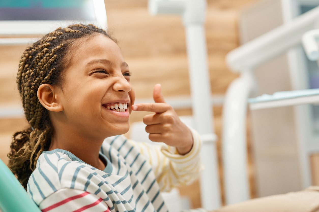 Girl pointing to her smile in a dentist's office