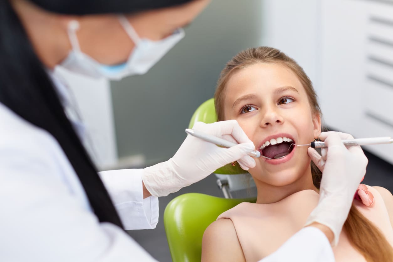 Dentist cleaning a girl's teeth